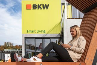 Pavillon Verkhershaus Luzern, Eingang zur Smart Living Ausstellung, Holzbank mit Dame am Handy drauf